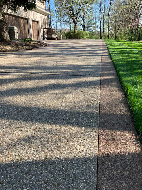 New stained, exposed aggregate concrete driveway with a stained border in Carmel, Indiana.