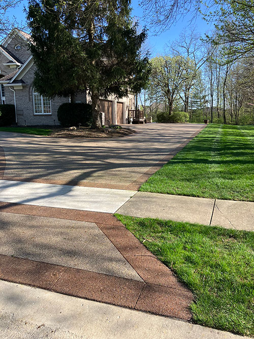 New stained, exposed aggregate concrete driveway with a stained border in Carmel, Indiana.