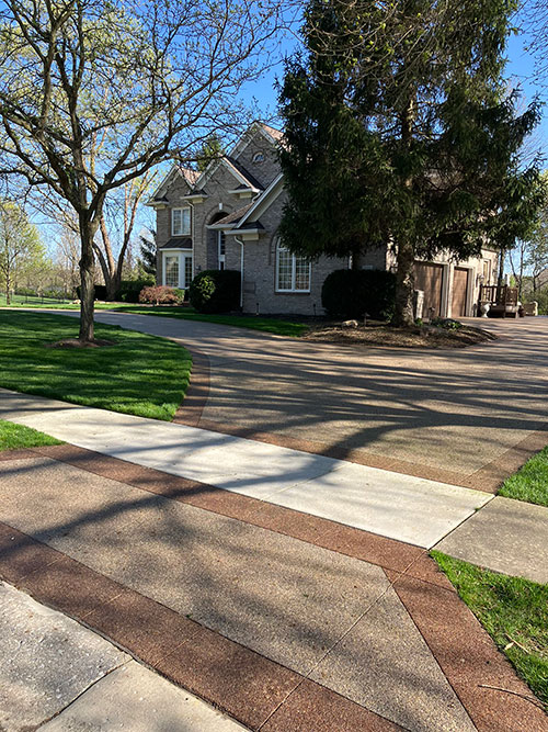 New stained, exposed aggregate concrete driveway with a stained border in Carmel, Indiana.