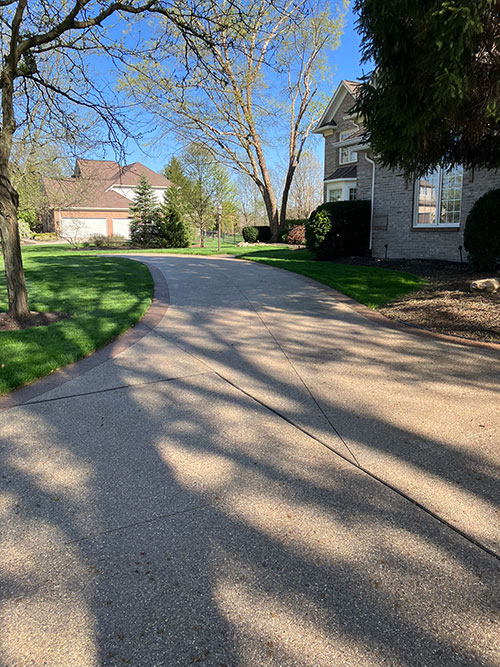 New stained, exposed aggregate concrete driveway with a stained border in Carmel, Indiana.