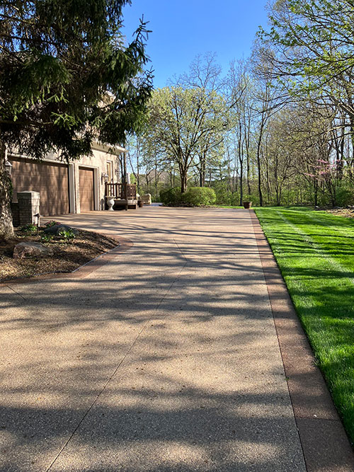 New stained, exposed aggregate concrete driveway with a stained border in Carmel, Indiana.