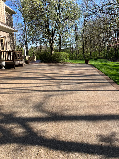 New stained, exposed aggregate concrete driveway with a stained border in Carmel, Indiana.